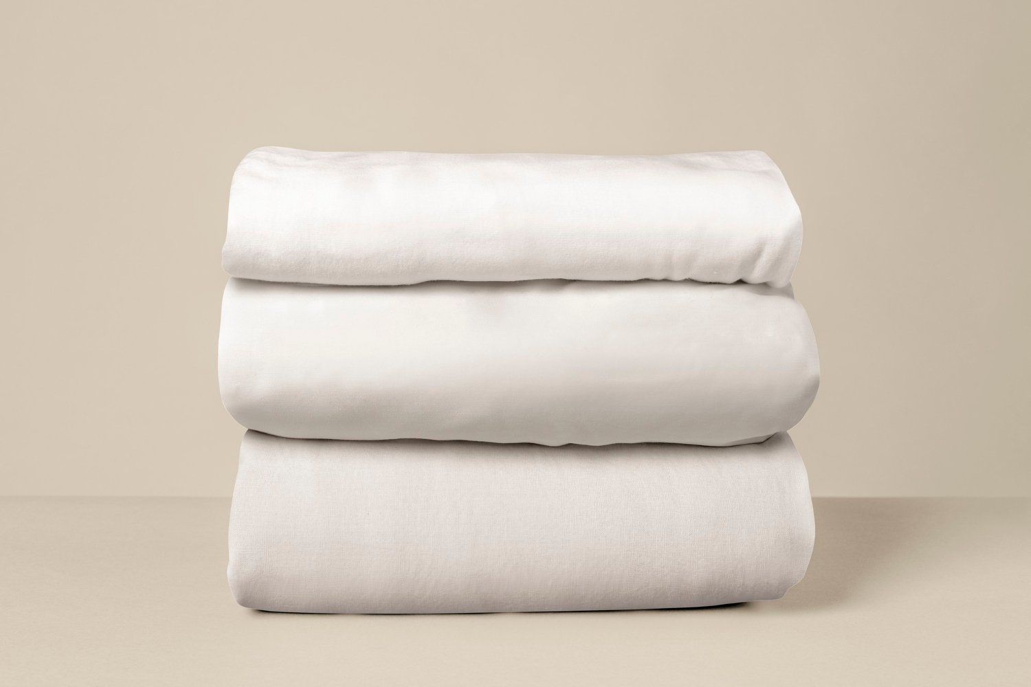Linge de lit blanc empilé sur un fond beige